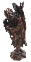 A late 19thC Qing dynasty hard wood carving of Shou Lao, modelled standing with his staff in one han