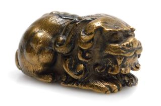 A 20thC Chinese bronze figure of a lion dog, modelled in recumbent pose, 5cm long.