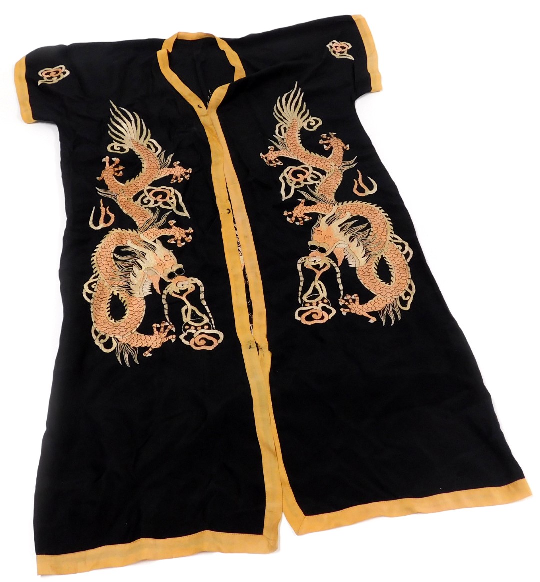 An early 20thC Chinese black silk short surcoat, embroidered with dragons in pink and white, with pe