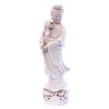 A 20thC Chinese blanc-de-chine porcelain figure of Guanyin, modelled standing holding a lotus flower