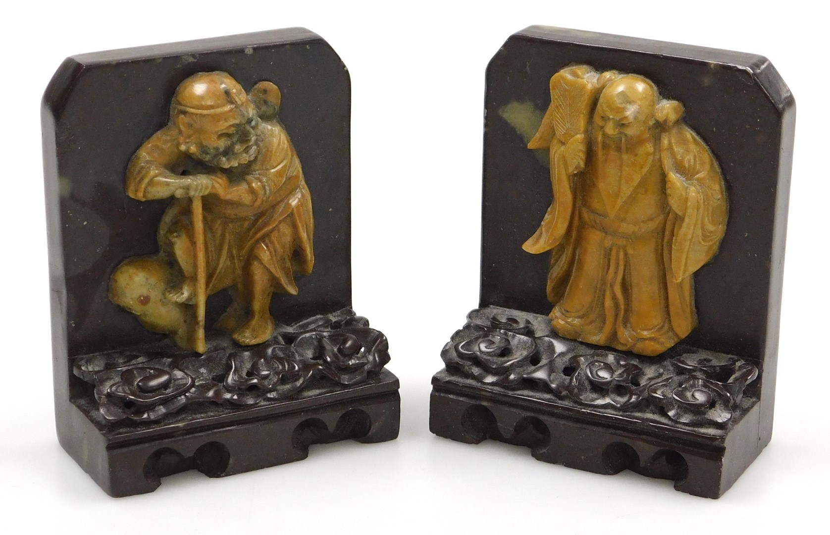 A pair of late 19thC Qing dynasty soapstone bookends, carved with immortals on a cloud ground, and c