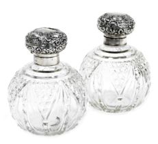 A pair of Edwardian cut glass and silver mounted scent bottles, the hinged lids embossed with shells
