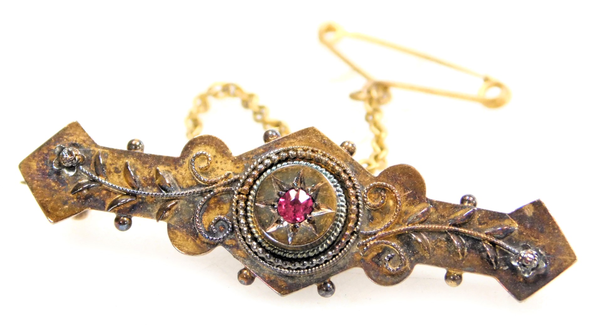 A Victorian brooch, set with a single ruby, yellow metal, stamped 15ct, with safety chain, 3.1g.