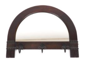 An Arts and Crafts style oak wall mirror, with a demi lune plate, and three iron hanging hooks, 59cm