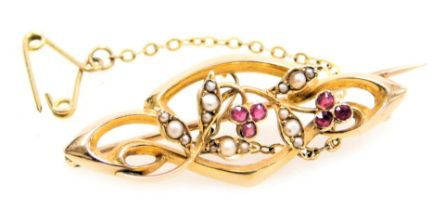 An Edwardian ruby and seed pearl brooch, in a scrolling floral and foliate design, in yellow metal,