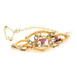 An Edwardian ruby and seed pearl brooch, in a scrolling floral and foliate design, in yellow metal,