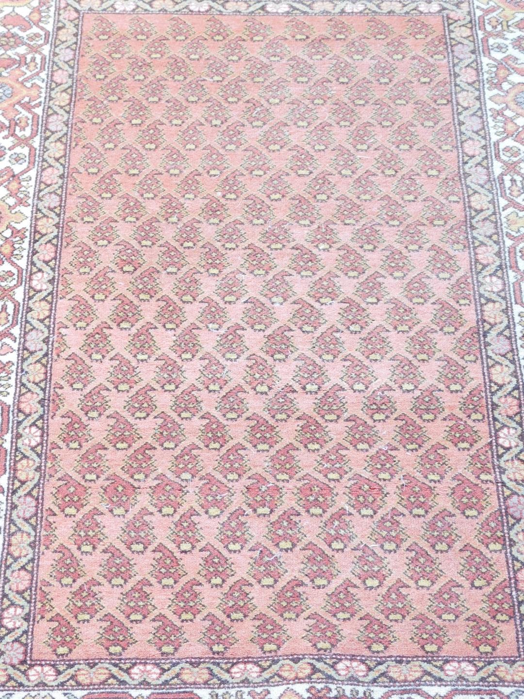 A caucasian red ground rug, the central field decorated with stylised botehs, within repeating flora - Image 2 of 3