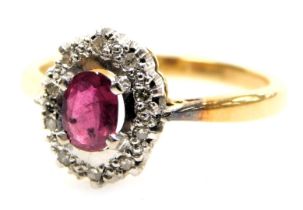 An 18ct gold ruby and diamond ring, the oval cut ruby in a basket setting with small diamonds, size