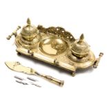 A Victorian brass desk stand, in the Ottoman style, with embossed foliate decoration, and a trench a