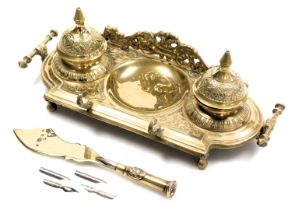 A Victorian brass desk stand, in the Ottoman style, with embossed foliate decoration, and a trench a