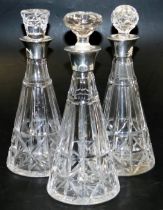 A set of three George VI cut glass decanters, of outswept form, with unmatched stoppers, and silver