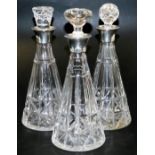 A set of three George VI cut glass decanters, of outswept form, with unmatched stoppers, and silver