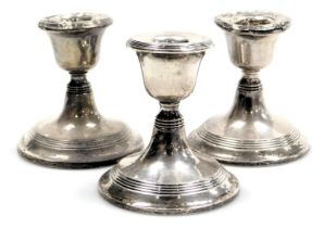 A pair of George V loaded silver candlesticks, Birmingham 1912, and a further loaded candlestick, Bi