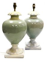 A pair of pottery table lamps, of fluted, baluster form, with a cream and celadon glaze, raised on a