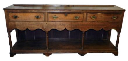 A George III oak and rosewood cross banded dresser base, with three long drawers, above a shaped apr