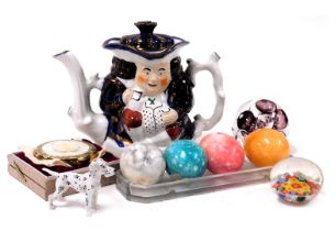 An early 20thC Alison's seated Toby teapot, glass paperweights, marble eggs, a compact, and a porcel