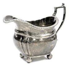 A Victorian silver cream jug, of fluted form, with an angular handle, raised on four ball feet, Lond