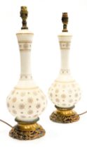 A pair of early 20thC milk glass and brass table lamps, of baluster form, gilt decorated with repeat
