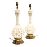 A pair of early 20thC milk glass and brass table lamps, of baluster form, gilt decorated with repeat