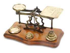A set of early 20thC brass postal scales, raised on a serpentine mahogany base, with weights, by Joh