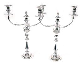 A pair of early 20thC silver plated twin branch candelabra, the central candle with a flame snuffer,