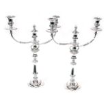 A pair of early 20thC silver plated twin branch candelabra, the central candle with a flame snuffer,