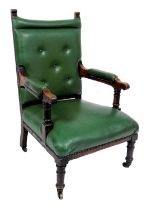 A Victorian oak armchair, upholstered in button back green leatherette, raised on turned legs, brass