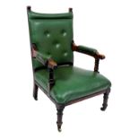 A Victorian oak armchair, upholstered in button back green leatherette, raised on turned legs, brass