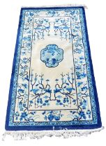A Chinese blue and cream ground rug, decorated with flowers and blossom, 187cm x 94cm.