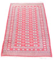 A Bokhara red ground rug, decorated with three rose of seventeen repeating medallions, within repeat