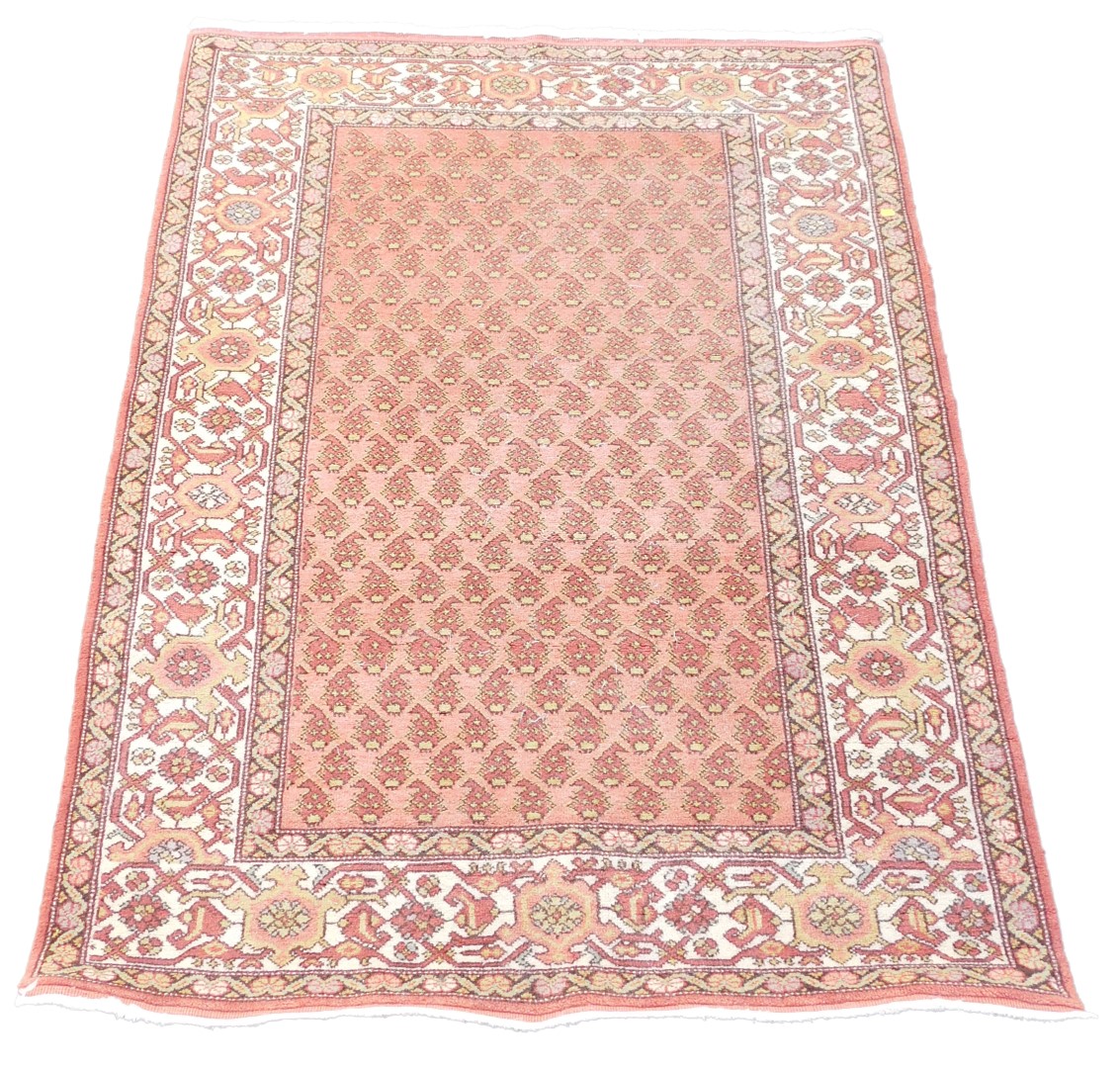 A caucasian red ground rug, the central field decorated with stylised botehs, within repeating flora