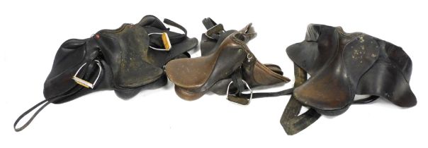 Three leather riding saddles, two with stirrups.