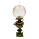 An early 20thC duplex brass and pottery oil lamp, with a brass reservoir, glass chimney and floral e