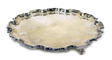 Elizabeth II silver pie crust salver, raised on three scroll feet, the underside presentation engrav