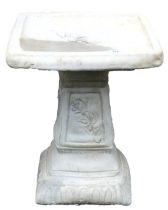 A concrete birdbath, with a square top, raised on a column with floral panels, 48cm high.