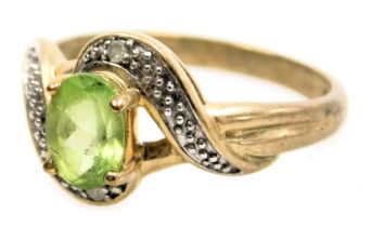 A 9ct gold peridot and diamond ring, in a cross over design, size N, 2.4g.