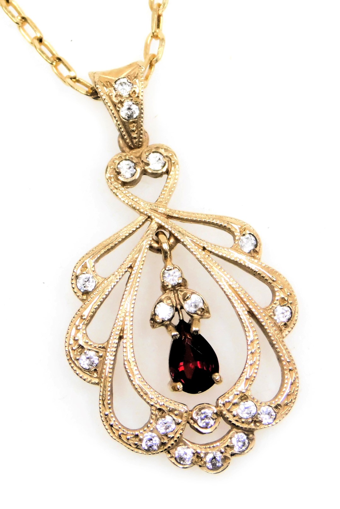 A 9ct gold ruby and diamond pendant in an Edwardian open work style, on a cable link neckchain, with