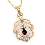 A 9ct gold ruby and diamond pendant in an Edwardian open work style, on a cable link neckchain, with