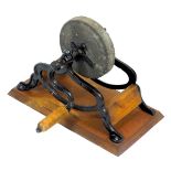 An early 20thC cast iron and stone knife grinder, with a wooden turning handle, raised on a rectangu