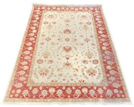 A Ziegler cream ground rug, decorated with floral motifs, within a red border, similarly decorated,