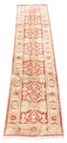 An Afghan red ground runner, decorated with repeating floral medallions and motifs, within repeating