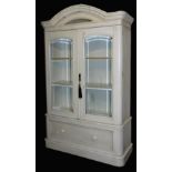 A 19thC French armoire, cream painted, with an outswept pediment, over two glass panelled doors encl