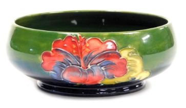 A Moorcroft pottery Hibiscus pattern bowl, green to blue ground, impressed marks, 14.5cm wide.