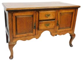 A Georgian style oak dresser base, with two short drawers flanked by a pair of cupboard doors, raise