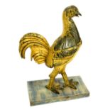 A 20thC gilded plaster figure of a rooster, raised on a rectangular wooden base, 68cm high.