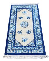A Chinese blue and cream ground rug, decorated with flowers and buddhist emblems, within repeating f