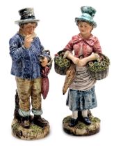 A pair of late 19thC French or Belgian pottery figures, of a lady with baskets of flowers, and a man