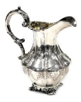 A Victorian silver cream jug, of fluted form, with engraved decoration, raised on four scroll feet,