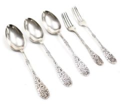 Three continental dessert spoons, with embossed stylised handles, together with a table fork and a d