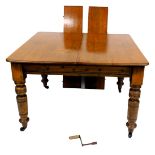 A Victorian oak wind out dining table, with two small additional leaves, raised on turned legs, on c